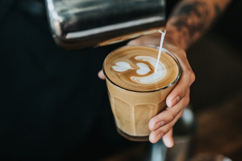 man pouring milk in coffee